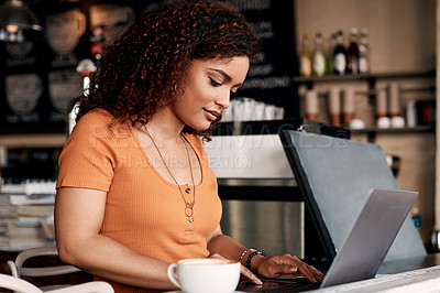 Buy stock photo Shot of a young woman working on a laptop in a cafe