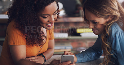 Buy stock photo Shot of two young women using a cellphone together in a cafe