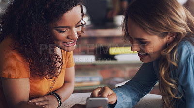 Buy stock photo Shot of two young women using a cellphone together in a cafe