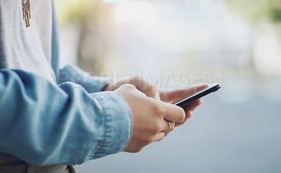 Buy stock photo Closeup shot of an unrecognisable woman using a cellphone while out in the city