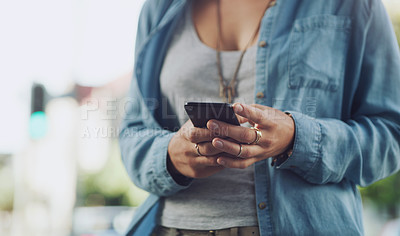 Buy stock photo Closeup shot of an unrecognisable woman using a cellphone while out in the city