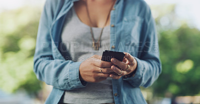 Buy stock photo Closeup shot of an unrecognisable woman using a cellphone while out in the city