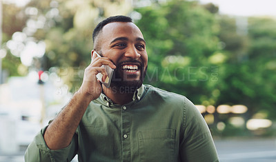 Buy stock photo Shot of a young man talking on a cellphone while out in the city