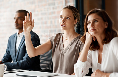 Buy stock photo Shot of an attractive young businesswoman sitting with her coworkers and raising her hand to ask a question