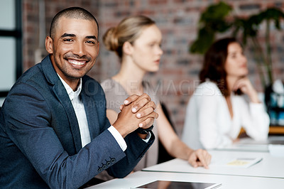 Buy stock photo Shot of a handsome young businessman sitting with his coworkers during a meeting in the office