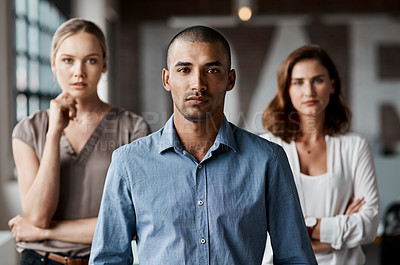 Buy stock photo Shot of a handsome young businessman standing with his coworkers in the office during the day