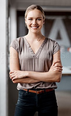 Buy stock photo Shot of an attractive young businesswoman standing alone in the office with her arms folded during the day