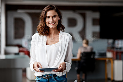 Buy stock photo Shot of an attractive young businesswoman standing alone in the office and using a digital tablet