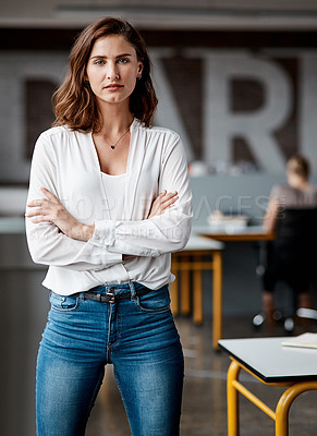 Buy stock photo Shot of an attractive young businesswoman standing alone in the office with her arms folded during the day