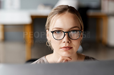 Buy stock photo Shot of an attractive young businesswoman sitting alone in the office and looking contemplative while using her computer