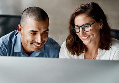 Buy stock photo Shot of two young businesspeople sitting together in the office and using a computer