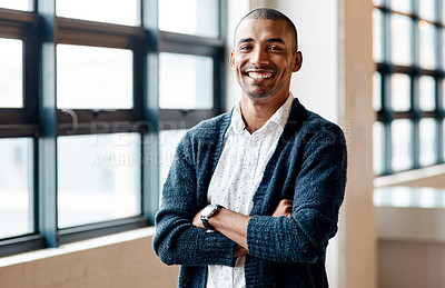 Buy stock photo Portrait of a confident young businessman standing with his arms crossed in an office