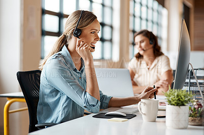 Buy stock photo Shot of a young businesswoman wearing a headset while working on a computer in an office