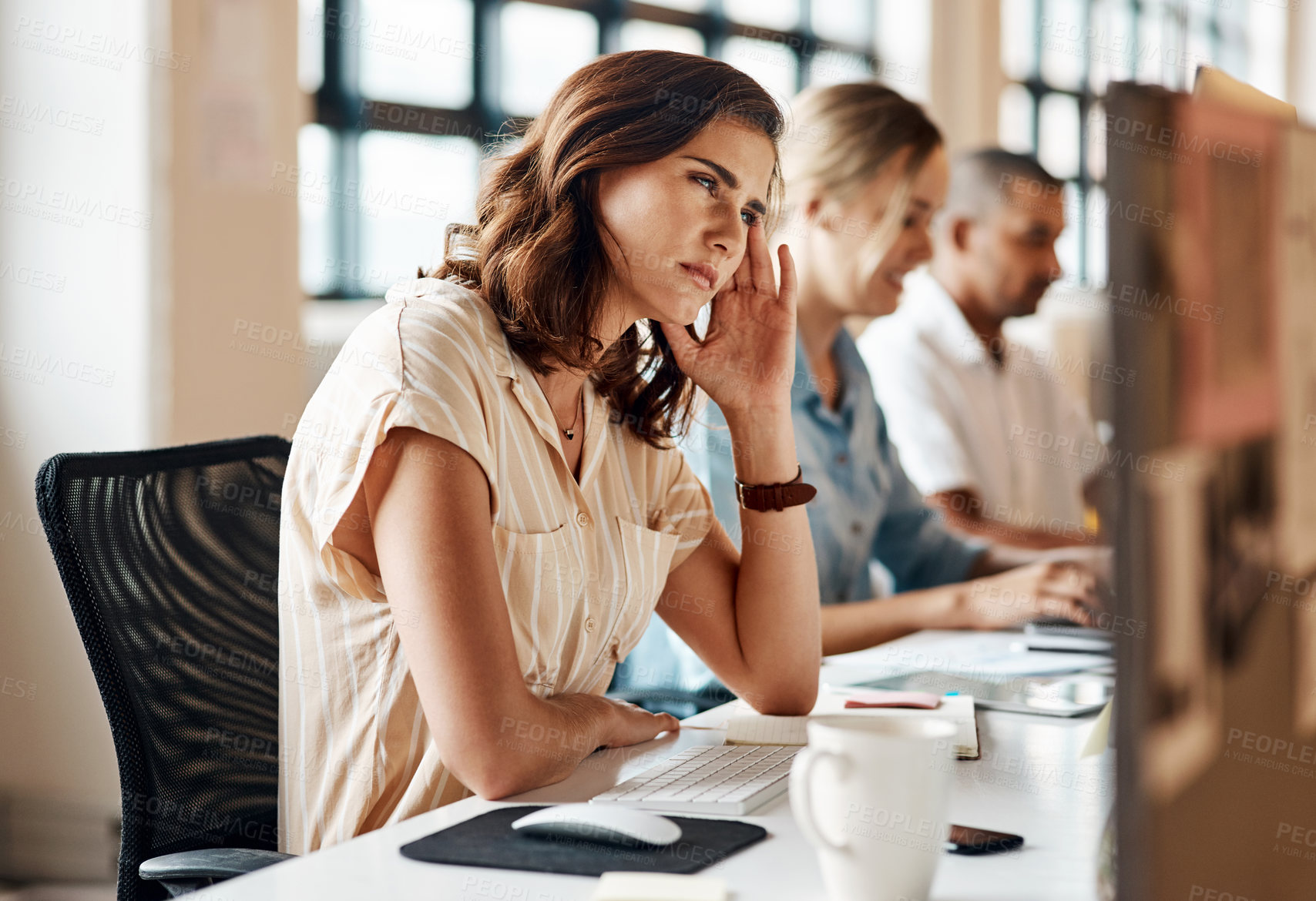 Buy stock photo Shot of a young businesswoman looking stressed out while working on a computer in an office