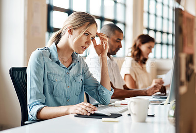 Buy stock photo Shot of a young businesswoman looking stressed out while working on a computer in an office
