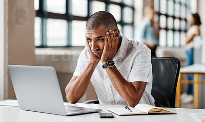 Buy stock photo Shot of a young businessman looking bored while working on a laptop in an office
