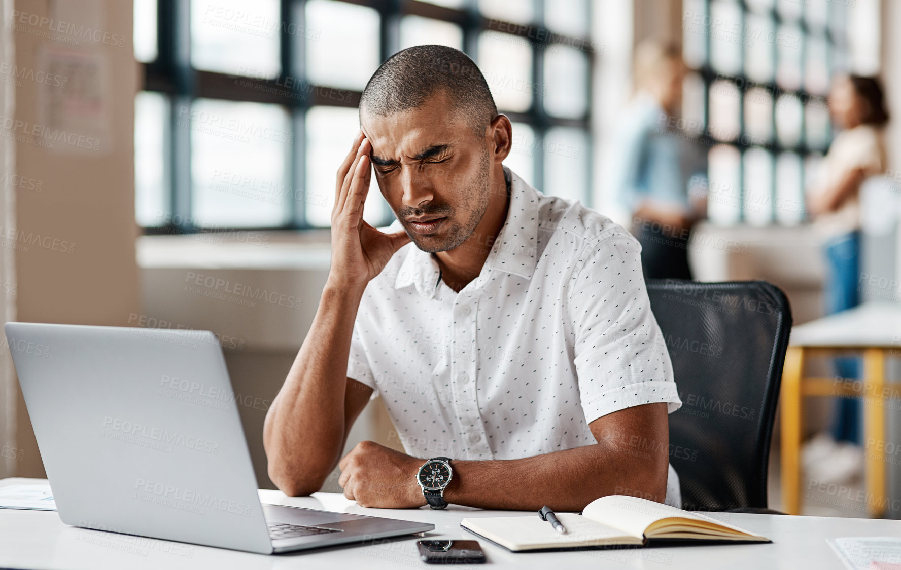 Buy stock photo Shot of a young businessman looking stressed out while working on a laptop in an office
