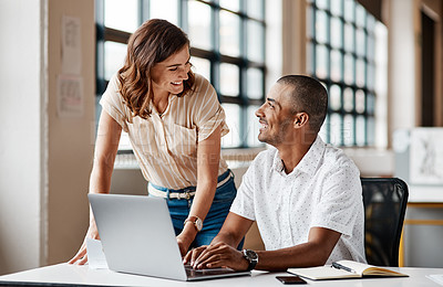 Buy stock photo Shot of two businesspeople working together on a laptop in an office