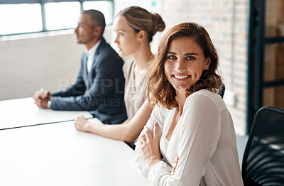 Buy stock photo Portrait of a young businesswoman sitting in an office with her colleagues in the background