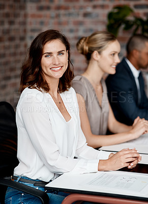 Buy stock photo Portrait of a young businesswoman sitting in an office with her colleagues in the background