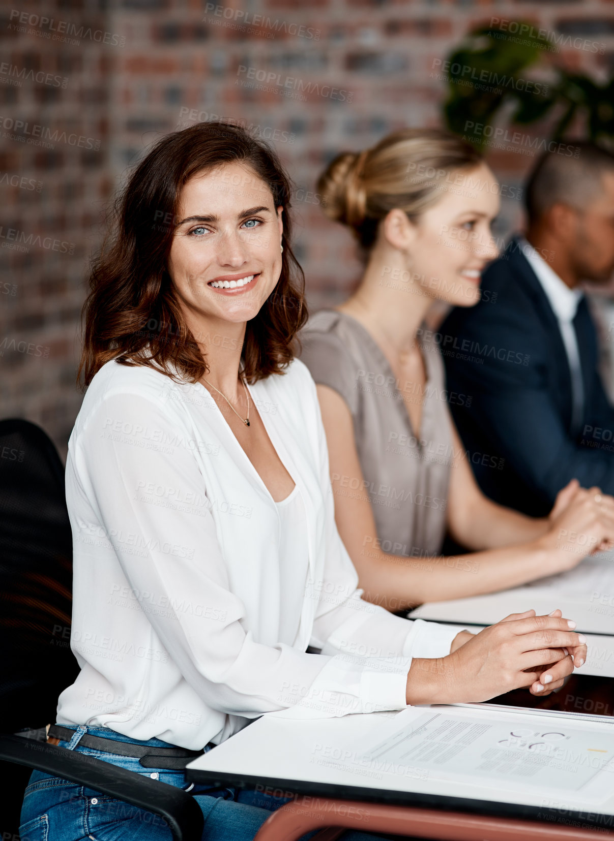 Buy stock photo Portrait of a young businesswoman sitting in an office with her colleagues in the background