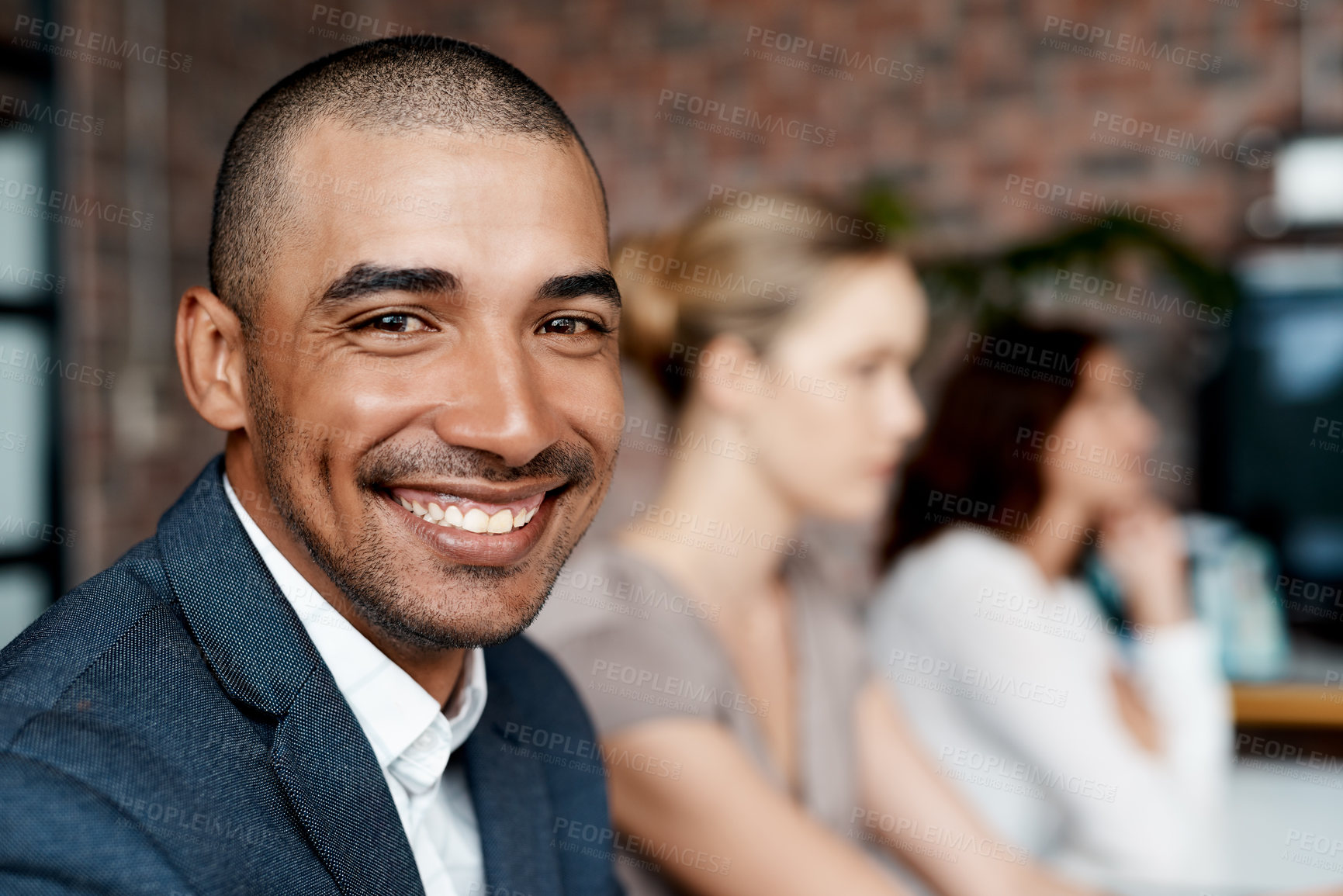 Buy stock photo Portrait of a young businessman sitting in an office with his colleagues in the background