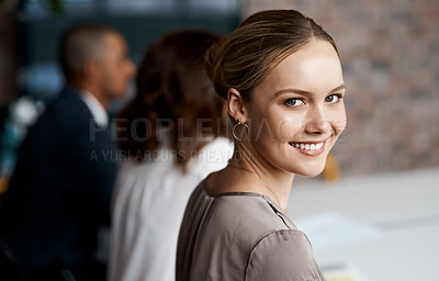 Buy stock photo Portrait of a young businesswoman sitting in an office with her colleagues in the background