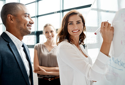 Buy stock photo Portrait of a young businesswoman brainstorming on a whiteboard with her colleagues in an office
