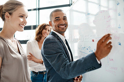 Buy stock photo Portrait of a young businessman brainstorming on a whiteboard with his colleagues in an office