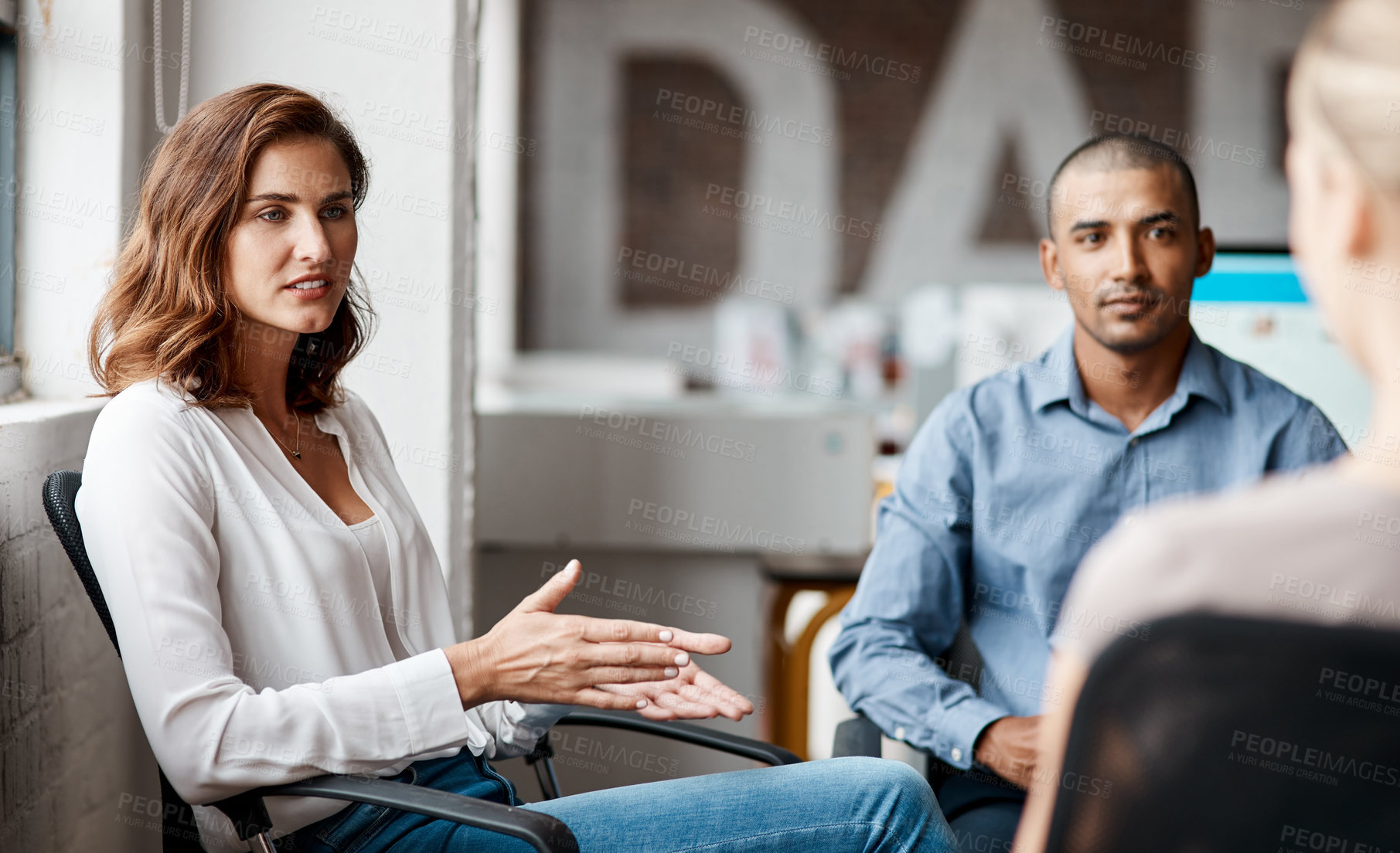 Buy stock photo Shot of a young businesswoman having a discussion with her colleagues in an office