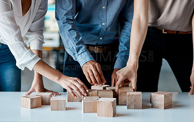 Buy stock photo Closeup shot of a group of unrecognisable businesspeople stacking building blocks together in an office