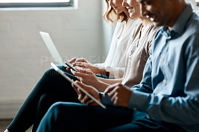 Buy stock photo Closeup shot of a group of unrecognisable businesspeople using digital devices while sitting in a row in an office