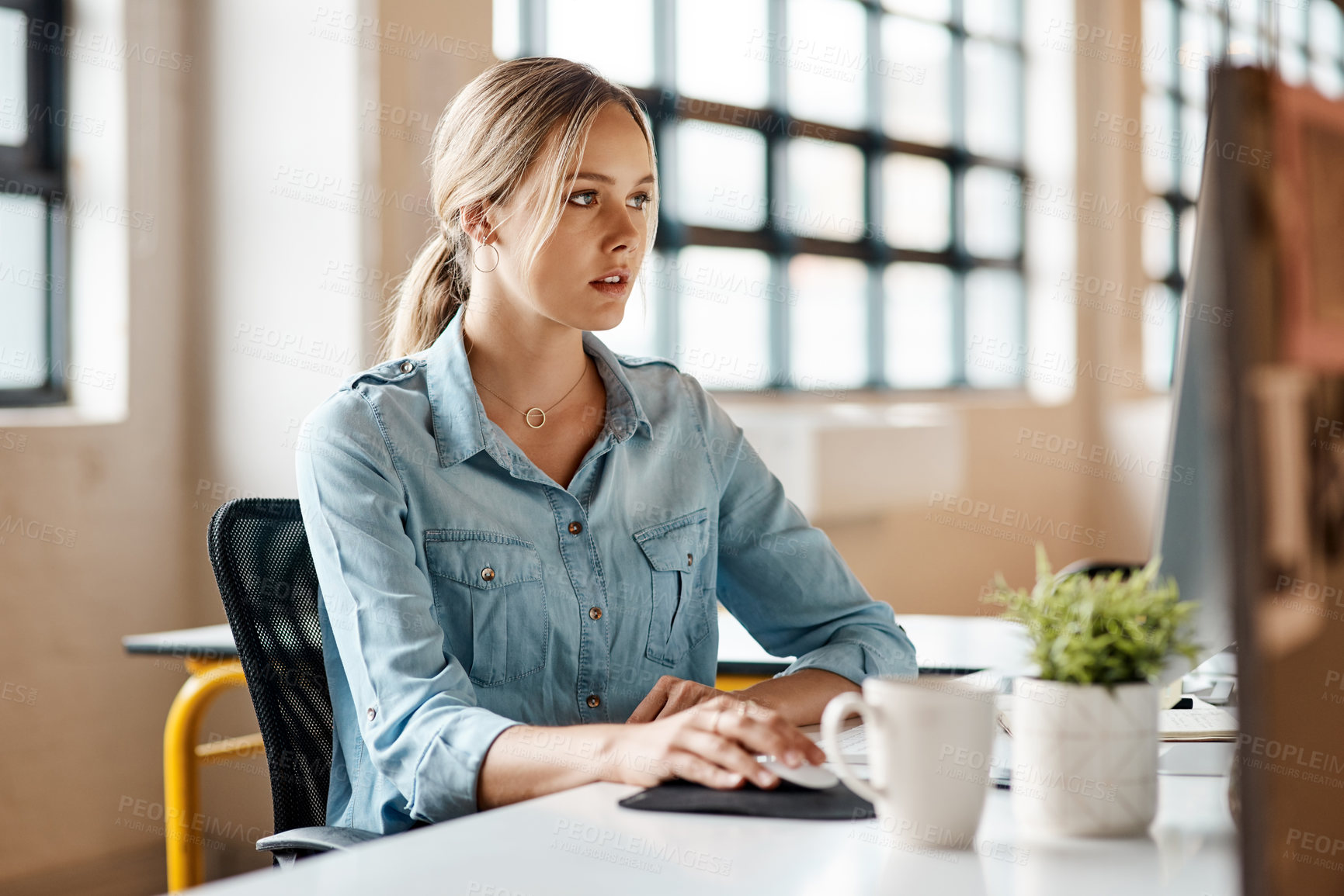 Buy stock photo Shot of a young businesswoman using a computer in a modern office