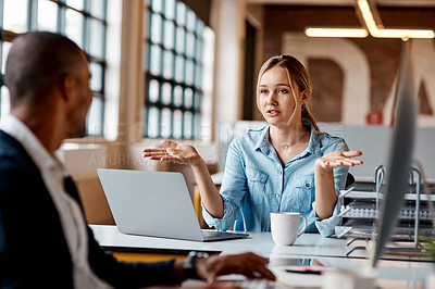 Buy stock photo Shot of a young businesswoman having a discussion with her colleague in a modern office