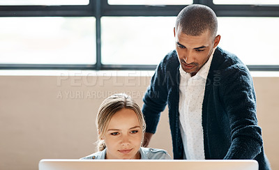 Buy stock photo Shot of a young businessman using a computer with his colleague in a modern office