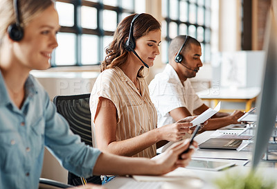 Buy stock photo Shot of a young woman using a headset and computer in a modern office