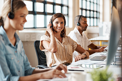 Buy stock photo Shot of a young woman using a headset and computer in a modern office