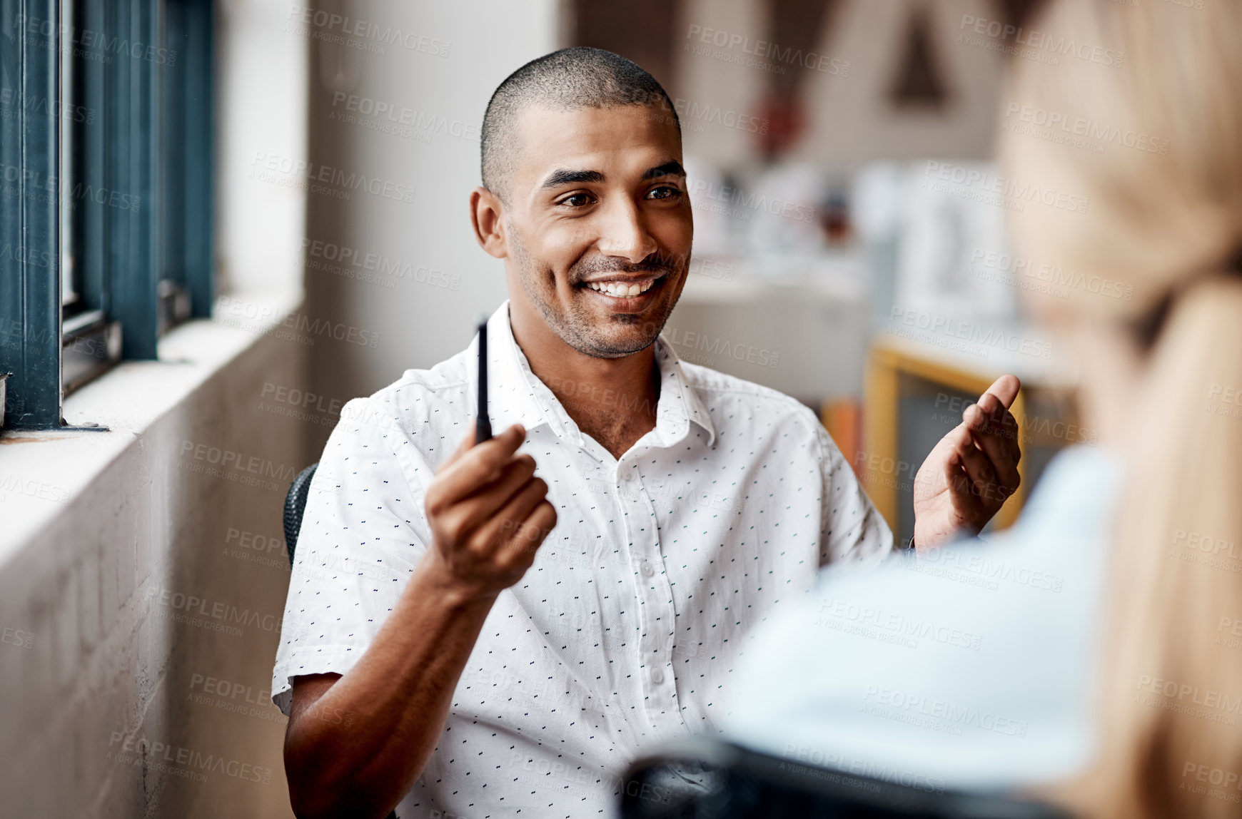 Buy stock photo Shot of a young businessman having a discussion with a colleague in a modern office