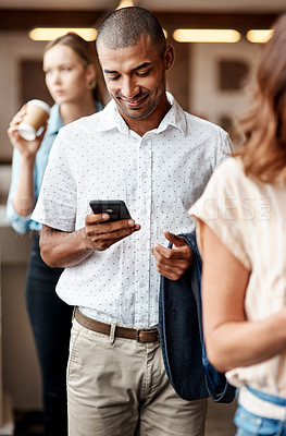 Buy stock photo Shot of a young businessman using a smartphone while waiting in line in a modern office