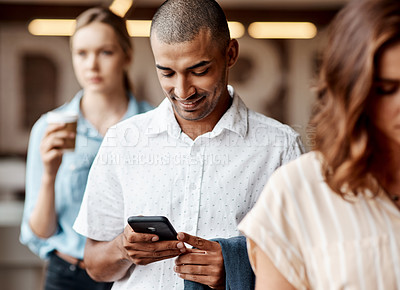 Buy stock photo Shot of a young businessman using a smartphone while waiting in line in a modern office