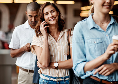 Buy stock photo Shot of a young businesswoman using a smartphone while waiting in line in a modern office