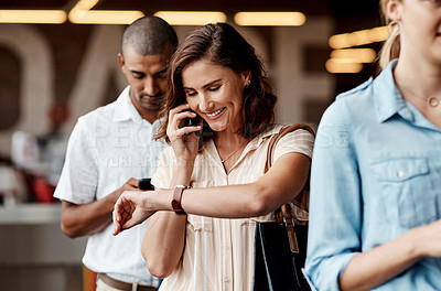 Buy stock photo Shot of a young businessman using a smartphone and checking the time while waiting in line in a modern office