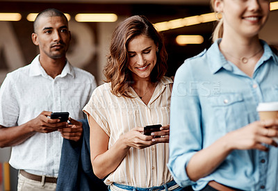 Buy stock photo Shot of a young businesswoman using a smartphone while waiting in line in a modern office