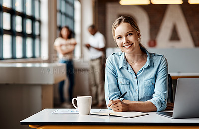 Buy stock photo Shot of a young businesswoman using a laptop and making notes in a modern office