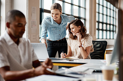 Buy stock photo Shot of a young businesswoman using a laptop with her colleague in a modern office