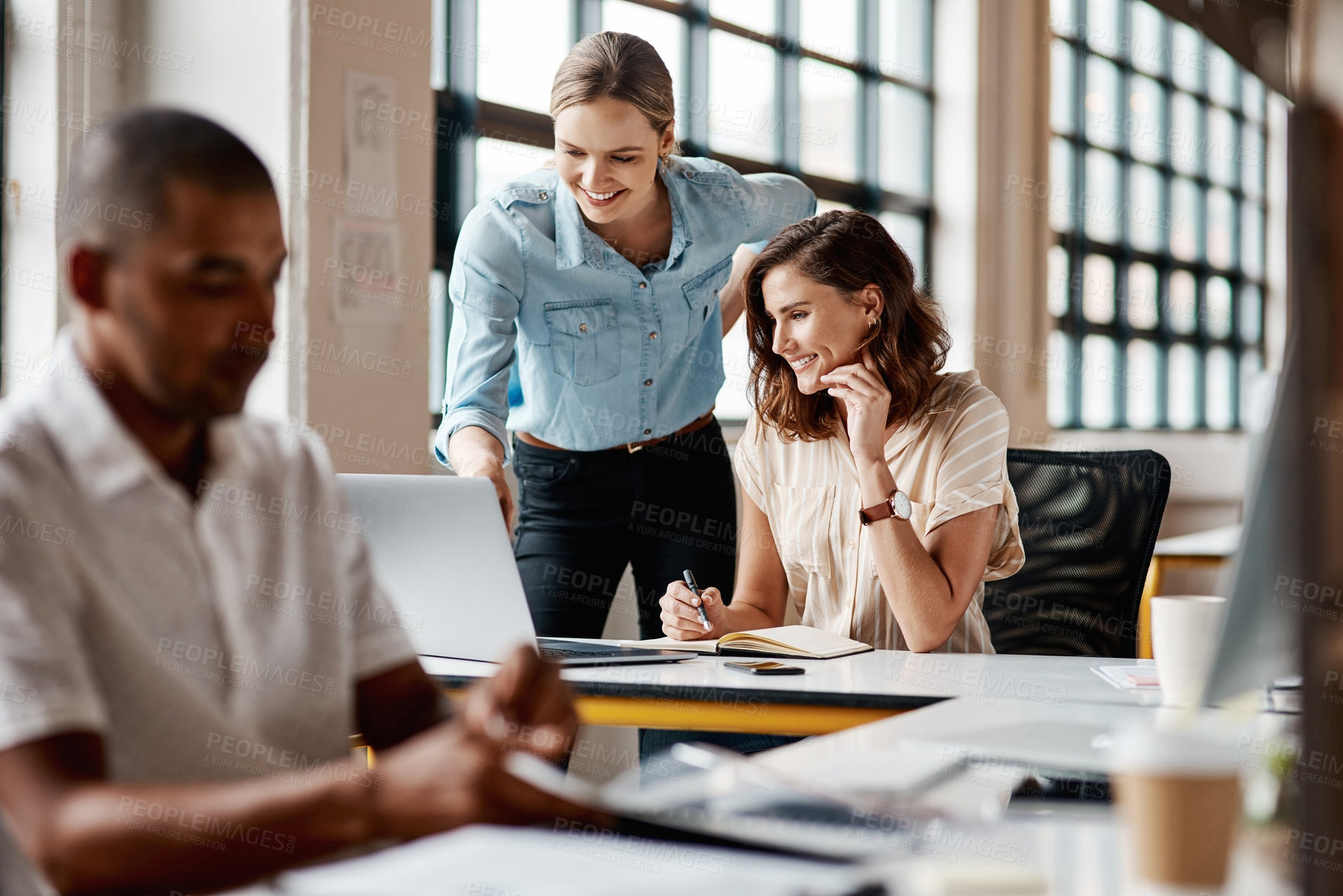 Buy stock photo Shot of a young businesswoman using a laptop with her colleague in a modern office