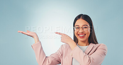 Buy stock photo Portrait, pointing and happy woman with palm in studio for advertising on a blue background. Female person, employee or smile with glasses, option or choice for marketing or presentation on space