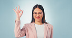 Portrait, perfect and happy woman in studio for review or feedback on a blue background. Female person, glasses or smile with like emoji, yes or OK sign for business success, opinion or perfection