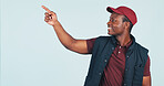 Pointing, space and delivery man in studio for ecommerce news, advertising and shipping info. Mockup, happy and African person with gesture for logistics, courier service and promo on blue background