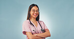 Arms folded, woman or nurse in studio for healthcare, portrait or cancer care on blue background space. Happy female person, medical worker or oncology professional with confidence, pride or about us